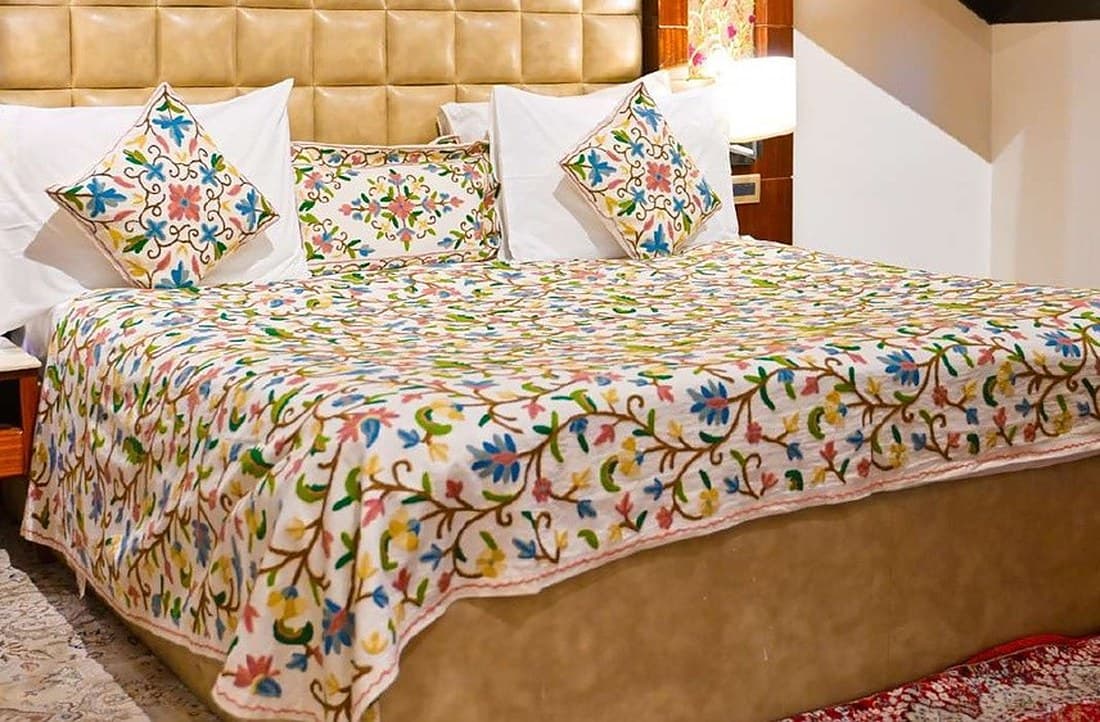 Ivory crewel bed ensemble in a suite